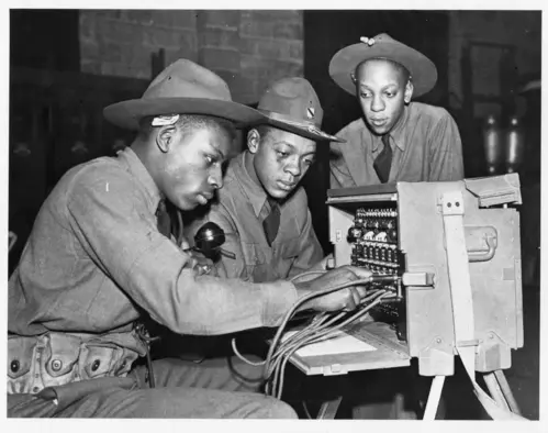 3 military men working on a portable phone switchboard