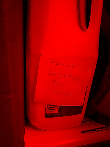 plastic half gallon of milk in the fridge with a post-it note that reads “Japanese Language Tea House”